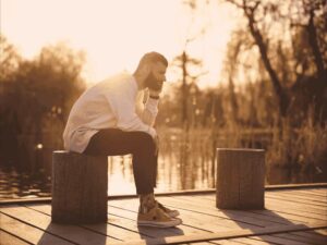 A man sites near a lake contemplating