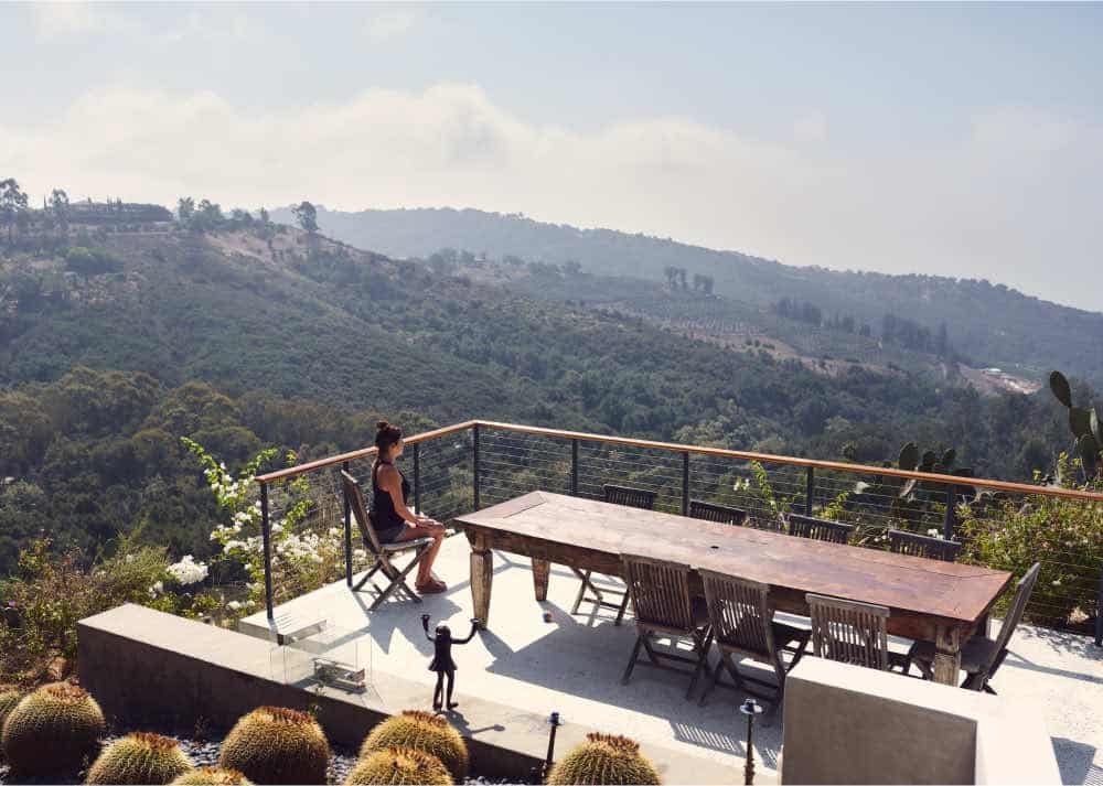 Woman meditating on a balcony overlooking mountains