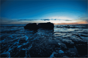The sun sets over a beach as the tide comes in