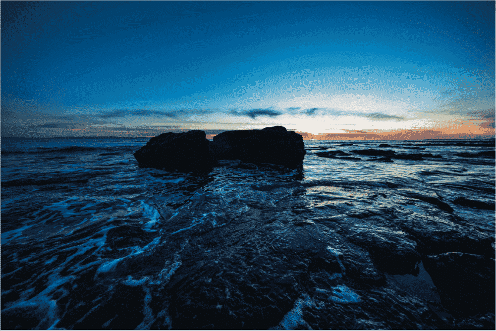 The sun sets over a beach as the tide comes in