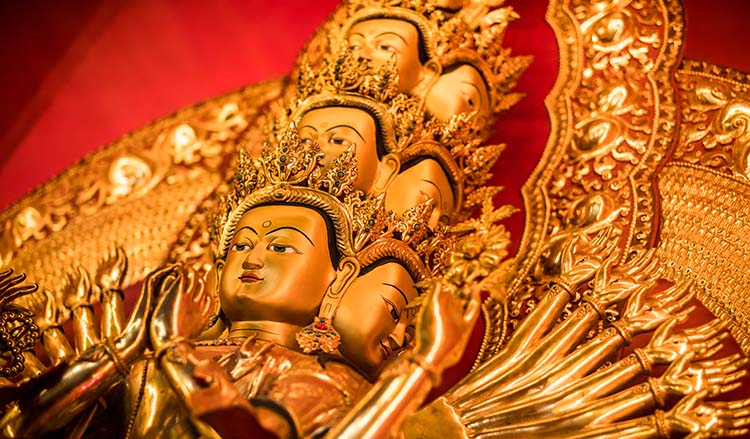 An image of a statue of a bodhisattva with many heads and arms, symbolizing limitless compassion and skillful means
